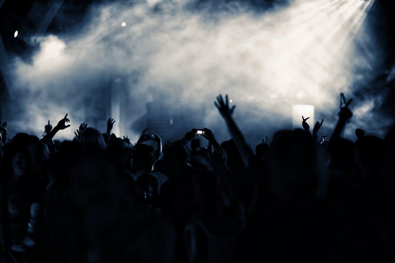 about-06 A lively nightclub concert scene with a cheering crowd illuminated by blue lights.